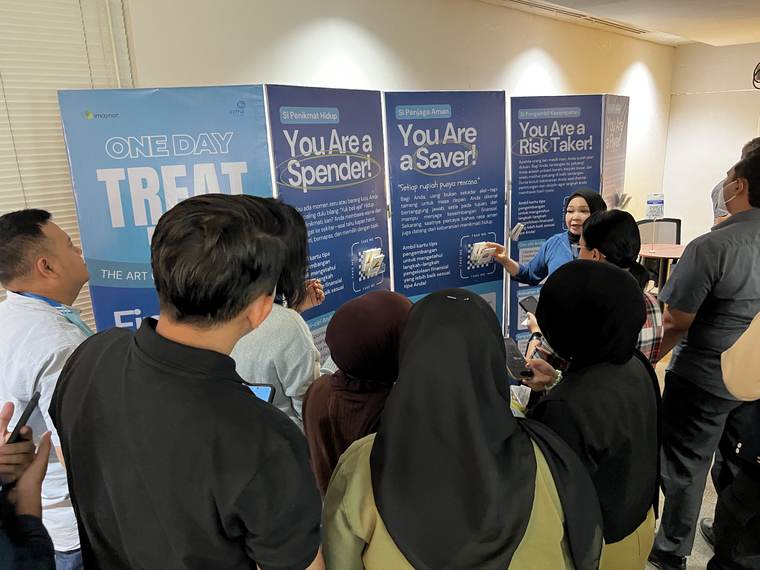 Peserta berkerumun di depan banner One Day Treat bertuliskan You Are a Spender, a Saver, dan a Risk Taker.