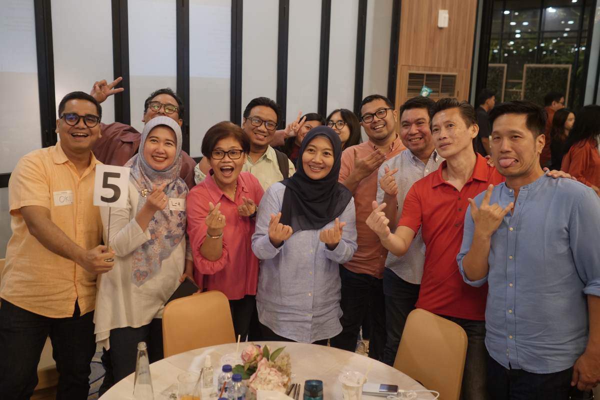 Belasan peserta berfoto bersama sambil membentuk tanda hati dengan jari, seusai sesi.